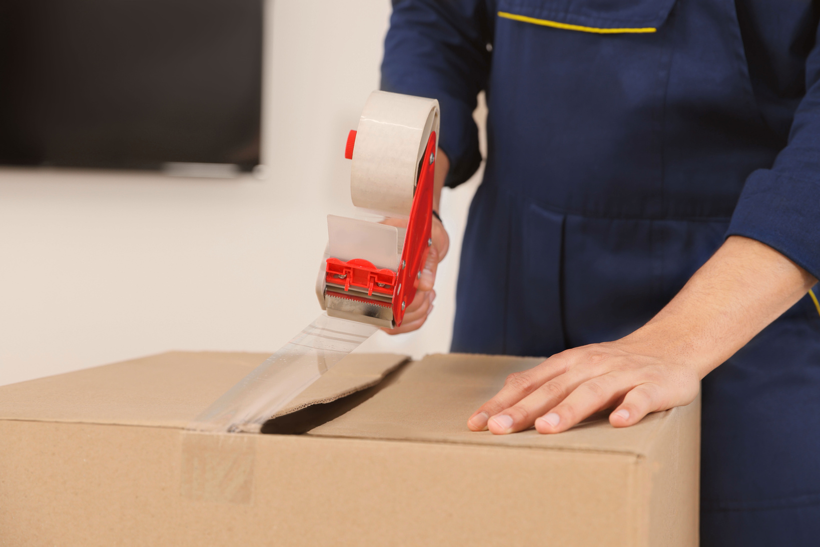 Male Mover Packing Box with Adhesive Tape Indoors, Closeup